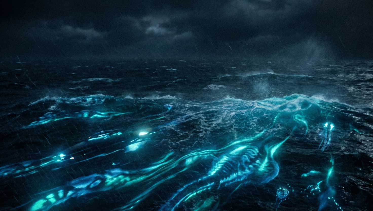 Underwater glowing lights moving beneath dark Pacific waves near a boat at night.